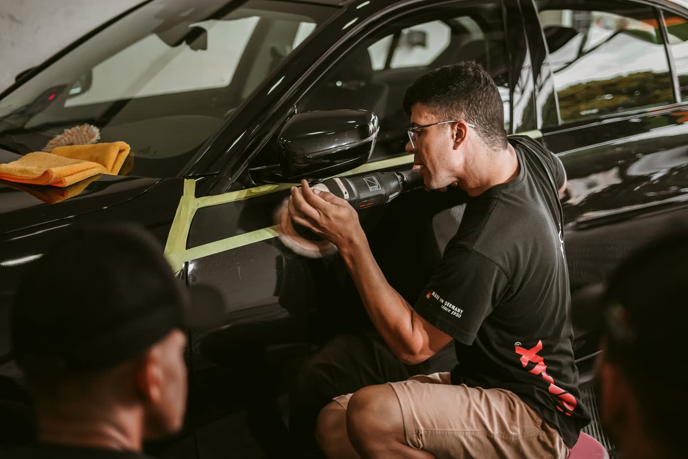 Detailer machine polishing the panel of a black car